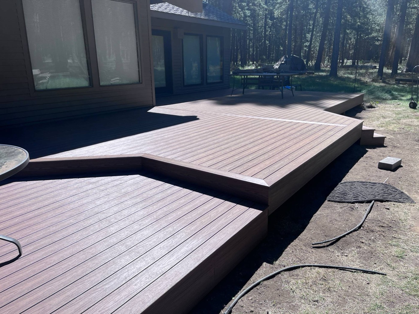 Composite deck stepping down along the back of the home into the pines